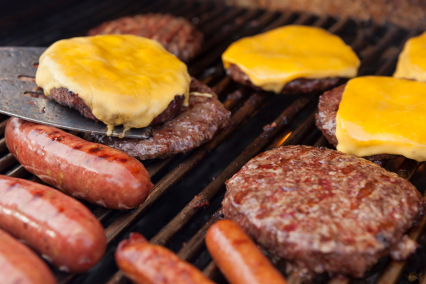 Cheeseburgers and hotdogs on a propane grill.