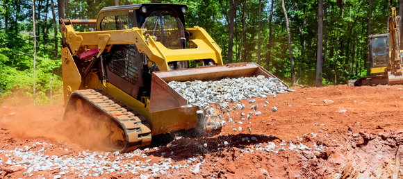A skid steer carrying gravel in its in bucket.