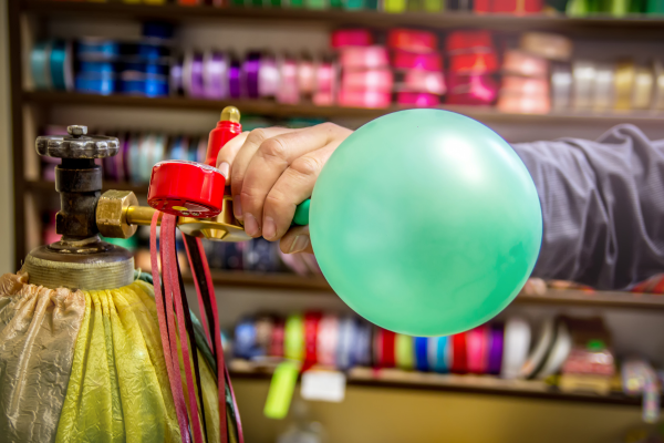 A blue helium balloon being blown up.